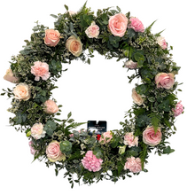 Load image into Gallery viewer, A round floral wreath with a variety of pink flowers, including roses and carnations, with green foliage.