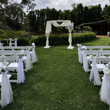 Load image into Gallery viewer, Wedding Ceremony Chair Flowers with white faux flowers and premium tulle styled on American chairs at Glen Ewin Estate Adelaide by Floral Atelier Australia.