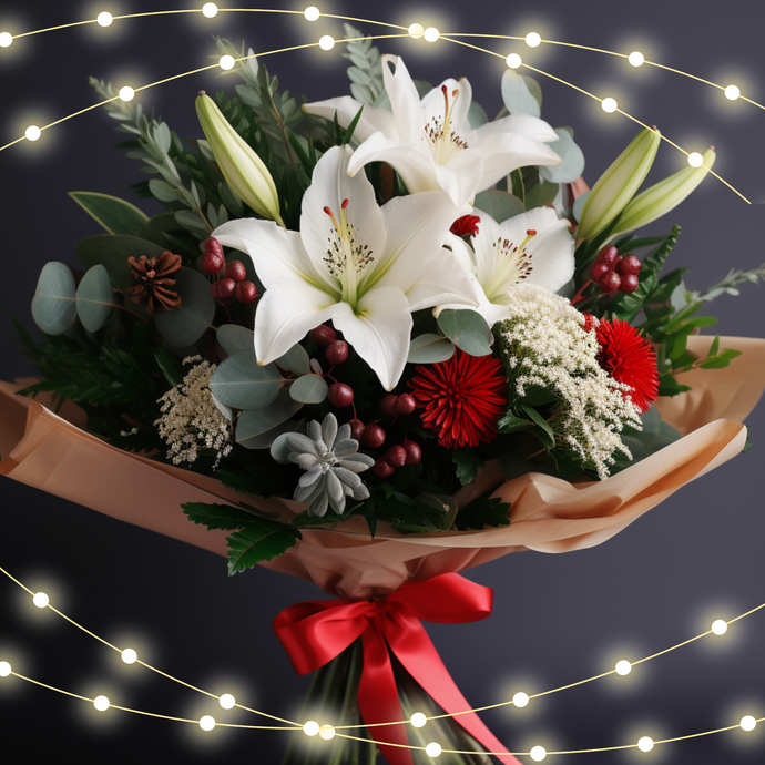 A festive Christmas bouquet featuring elegant white lilies, red berries, and touches of silver and greenery. The arrangement is wrapped in soft golden paper and tied with a bright red ribbon. This bouquet radiates warmth and joy, perfectly symbolizing heartfelt Christmas wishes sent to loved ones in Adelaide.