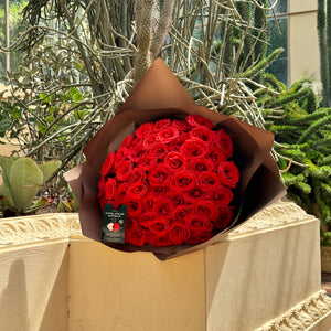 Floral Atelier Australia's Elegant 50 Ferrari Red Roses Bouquet stands out with its vibrant color against a backdrop of serene cacti, embodying Adelaide's unique natural beauty, ready for same day flower delivery