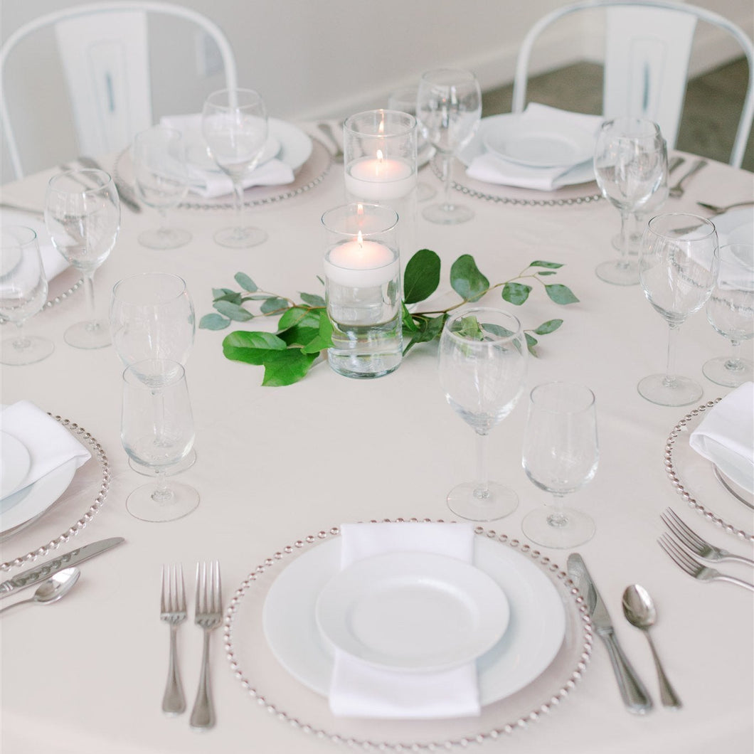 Floating candles in glass vases with fresh foliage – small wedding or event table decor by Floral Atelier Australia.