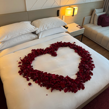 Load image into Gallery viewer, Bed with heart-shaped arrangement of red rose petals in a bedroom setting in Adelaide
