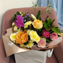 Load image into Gallery viewer, a bouquet of flowers roses and orchid and magnolia in a paper bag
