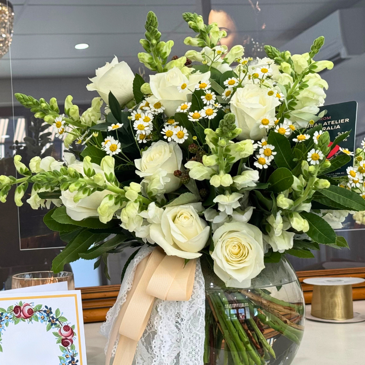 A Monte Bianco bouquet featuring fresh white roses, seasonal flowers, and lush foliage, arranged as a classic hand-tied bouquet with soft ribbons or in a vase with decorative ribbons, ideal for natural, serene, or passionate themes.