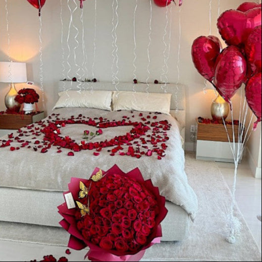 Fresh red rose petals forming a heart on the bed and pathway to the bed, paired with a luxurious bouquet of 100 long-stem red roses from Floral Atelier Australia.