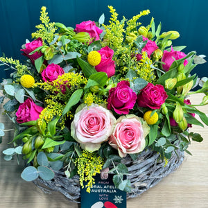 A stunning vibrant rose arrangement with 2 pink roses, 10 hot pink roses, 5 alstroemerias, 4 yellow billy buttons, and rich foliage of golden rod and blue gum. The deluxe size creates a fuller and more impactful display, ideal for making a bold and joyful statement.