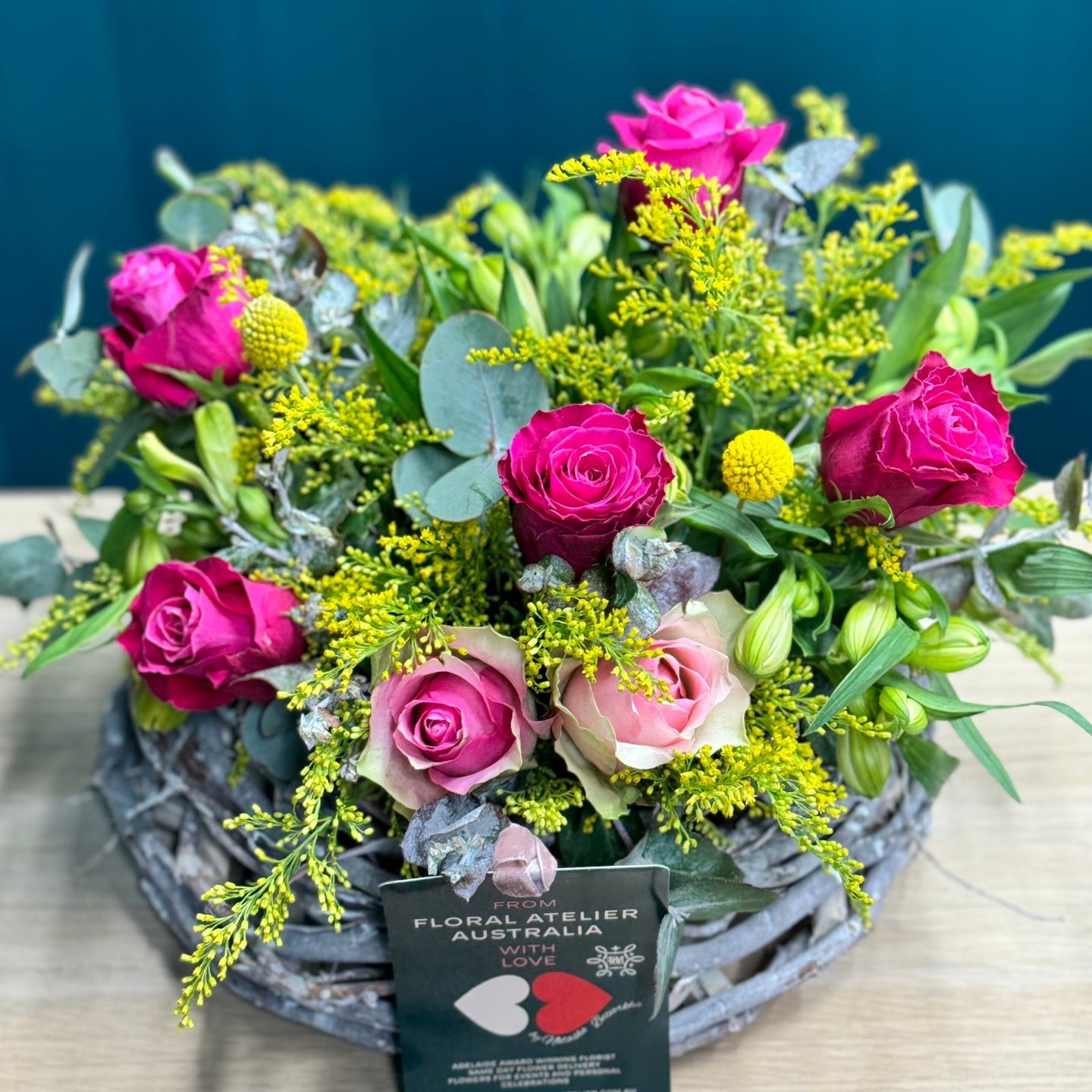 A vibrant rose arrangement featuring 2 pink roses, 5 hot pink roses, 5 alstroemerias, 2 yellow billy buttons, and lush greenery of golden rod and blue gum. The standard size offers a balanced display of bright colors, perfect for adding a lively and cheerful touch to any setting.