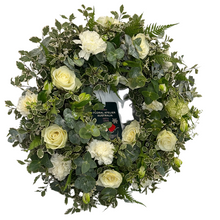 Load image into Gallery viewer, Floral wreath with white flowers and greenery, featuring a brand label.
