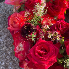 Load image into Gallery viewer, Close-up image of the Red Rose Wreath, showcasing the intricate details of the vibrant red roses, seasonal flowers, and lush greenery in a harmonious composition
