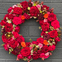 Load image into Gallery viewer, Red Rose Wreath elegantly displayed on a wall, featuring a vibrant mix of fragrant red roses, seasonal flowers, and lush greenery in a beautiful circular design.
