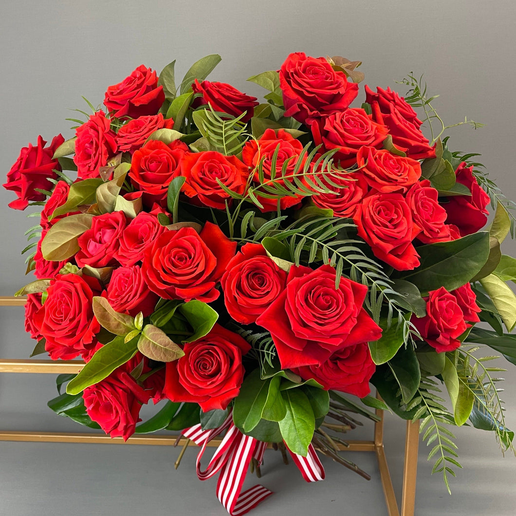 40 red roses in a round bouquet with greenary