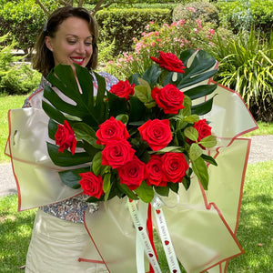 Red roses vor valentines day. Modern Wrapping, scarlet red roses, young women smiling and happy.